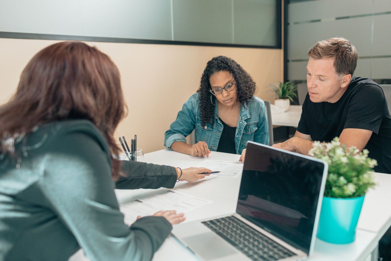 A man and woman review a document with an advisor across a table.